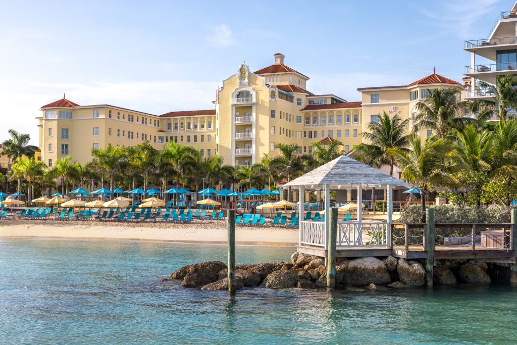 resort with beach in front, beach lounge chairs and palm trees